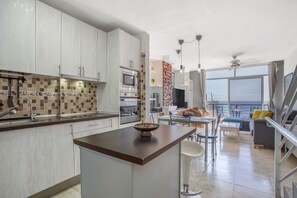 Une cuisine moderne dotée d’un îlot central, d’un coin repas offrant une vue agréable et d’un espace de vie avec balcon.