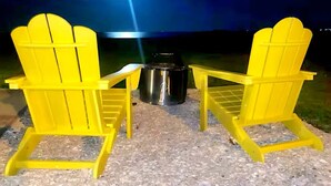 Two yellow Adirondack chairs, a stainless steel pot, and a small table on a gravel surface at night. - Waterfront, Lighted Pier and Family Games! (Port Lavaca)
