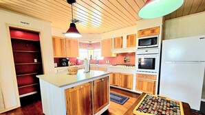 A kitchen with wooden cabinets, a white island, a microwave, an oven, and a refrigerator. - Waterfront, Lighted Pier and Family Games! (Port Lavaca)