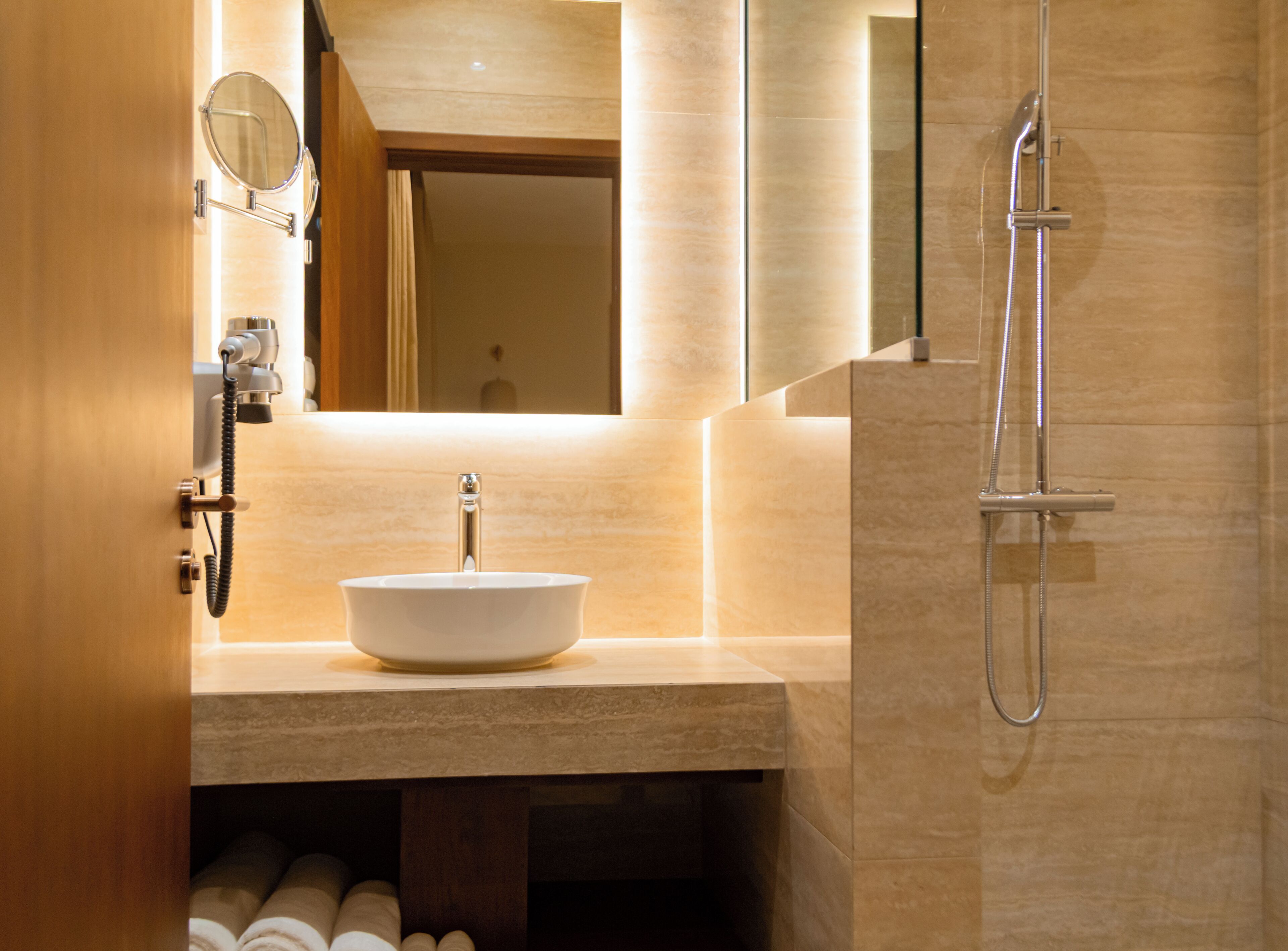 A bathroom with a white sink, a mirror, a shower, and a towel rack.