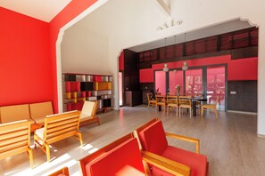 A spacious room with a dining area, a sofa set, and a bookshelf.