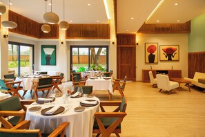 A dining area with round tables, chairs, and a view of the outdoors. - Native Hotels (Ouidah)