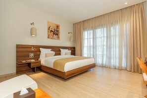 Une chambre d’hôtel moderne avec un grand lit, une tête de lit en bois, des tables de chevet, un bureau et une fenêtre avec des rideaux.