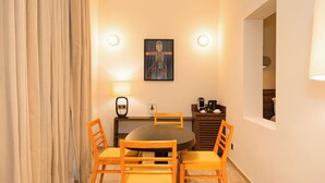 Un comedor con una mesa redonda, cuatro sillas de madera, un cuadro en la pared y una lámpara.