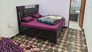 Ein Schlafzimmer mit einem Bett, einem Nachttisch, einer Steckdose und einem durch eine offene Tür einsehbaren Badezimmer.