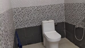 Ein Badezimmer mit Toilette, Dusche und Fliesen.