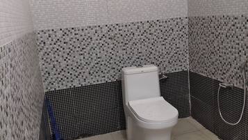 A bathroom with a toilet, a shower, and tiled walls.