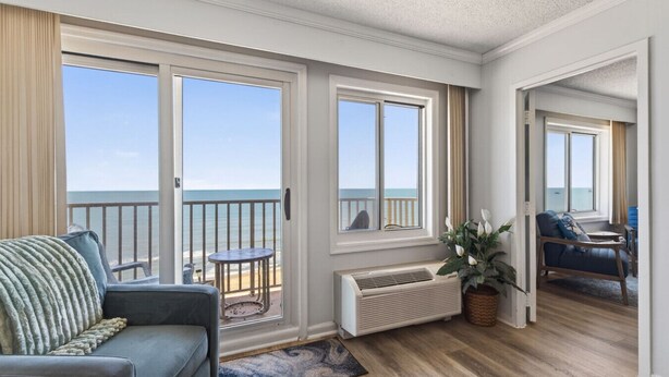Een kamer met balkon, een bank, een tafeltje en een bloempot.