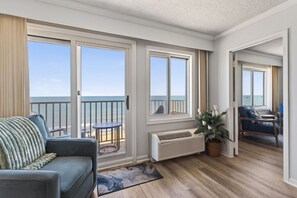 A room with a balcony, a sofa, a small table, and a potted plant. - Oceanfront Beach Condo, Pool, Gym, Fishing Surfing (Virginia Beach)