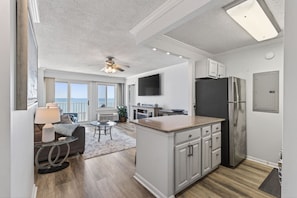 A modern kitchen with a central island, a dining area with a table and chairs, and a living area with a sofa and a lamp.