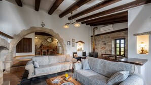 A cozy living area with two patterned sofas, a wooden coffee table, and a stone fireplace. - Altair Blue Villa - Private Jacuzzi and Views (Kalo Chorio)