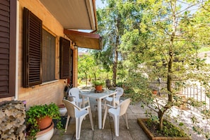 Un patio con tavolo e sedie, una pianta in vaso e un muro in mattoni.