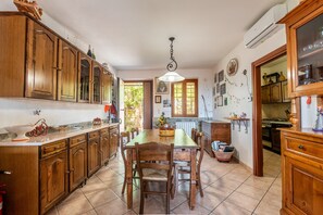 Una cucina con mobili in legno, un tavolo da pranzo, sedie e una lampada a sospensione.
