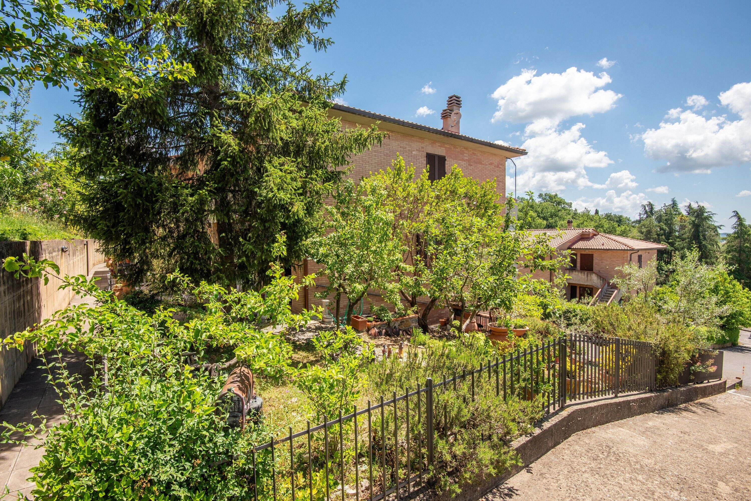A brick building with a garden, a metal fence, and a clear sky.