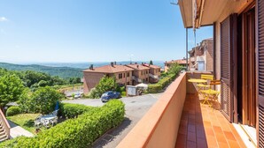 A residential balcony with a view of a residential area, a car parked in the driveway, and a clear sky.