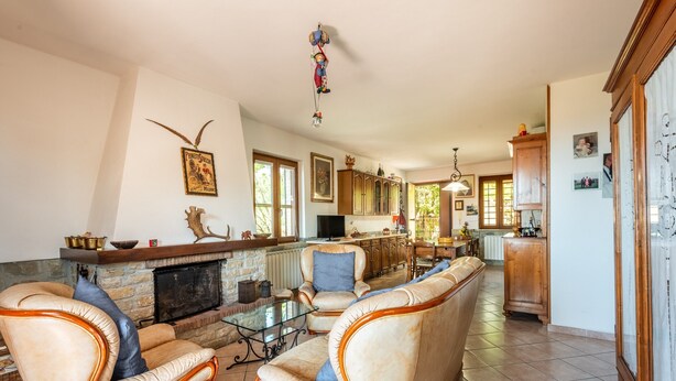 A spacious living room with leather sofas, a fireplace, and a kitchen in the background.