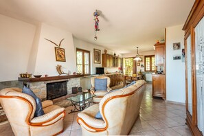 Amplia sala de estar con sofás de cuero, chimenea y cocina al fondo.