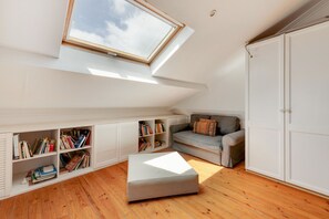 Una habitación con tragaluces, un sofá, una estantería y un armario.