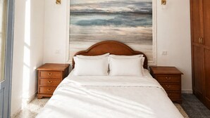 Ein Schlafzimmer mit einem Bett, einem Meeresbild, einer Chandelüster und Holzmöbeln.