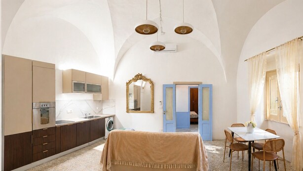 Ein kleines Zimmer mit Küchenzeile, Essbereich und Bett.
