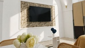 Ein modernes Wohnzimmer mit einem Marmortisch, einer weißen Vase mit Blumen, einem flachbildfernseher an einer strukturierten Wand und einem Sofa.