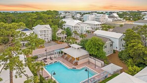 A residential area with a swimming pool, multiple houses, and a view of the ocean. - Sea Charm | Close to Beach | Golf Cart (LSV) | Community Pool (Santa Rosa Beach)