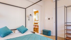 Ein Schlafzimmer mit Bett, Kleiderschrank und angrenzendem Badezimmer, das durch eine offene Tür sichtbar ist.