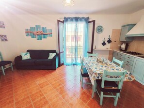 A compact living space with a dining area, kitchenette, and a sofa with a cushion. - Vacation home san vito lo capo CristalMar (Sicilia)
