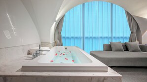 A modern bathroom with a large bathtub, a sofa, and a view of the city. - ASPERA HIGH-ALTITUDE GARDEN PANORAMIC (Chongqing)
