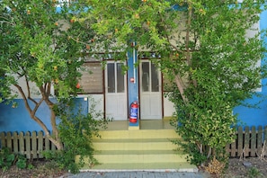 A building with a blue exterior, a wooden fence, and a fire extinguisher on the steps.
