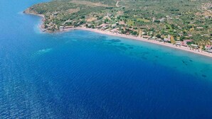 Vista aérea de una zona costera con playa, edificios y colinas verdes.