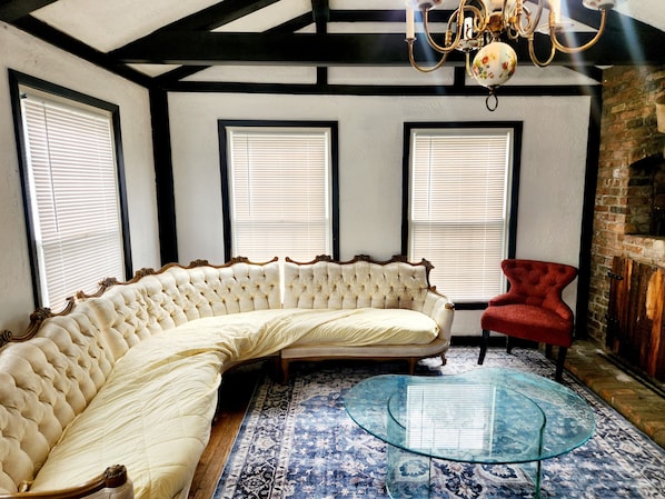 A room with a curved white sofa, a red chair, a glass coffee table, and a patterned rug.