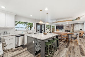 Una cocina moderna con una isla grande, taburetes de bar y vistas al exterior.