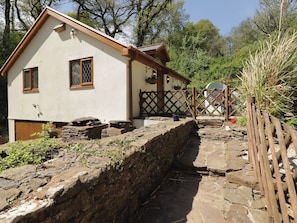 A rustic house with a stone wall, wooden fence, and a wooden gate.