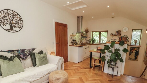 A cozy living room with a sofa, ottoman, and a dining area with a table and chairs.