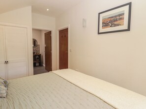 A bedroom with a bed, a wardrobe, a mirror, and a framed picture on the wall.