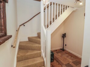 Un escalier avec une main courante en bois, des marches recouvertes de moquette, une rampe blanche et un lampadaire.