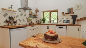 A kitchen with a wooden table, a microwave, and a window with blinds.