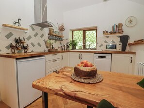 A kitchen with a wooden table, a microwave, and a window with blinds.