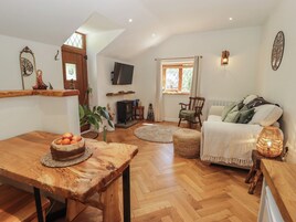 Una sala de estar acogedora con una mesa de madera, un sofá, un televisor y una chimenea.