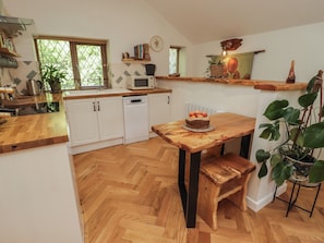 A kitchen with wooden cabinets, a microwave, a sink, and a wooden dining table with a cake.