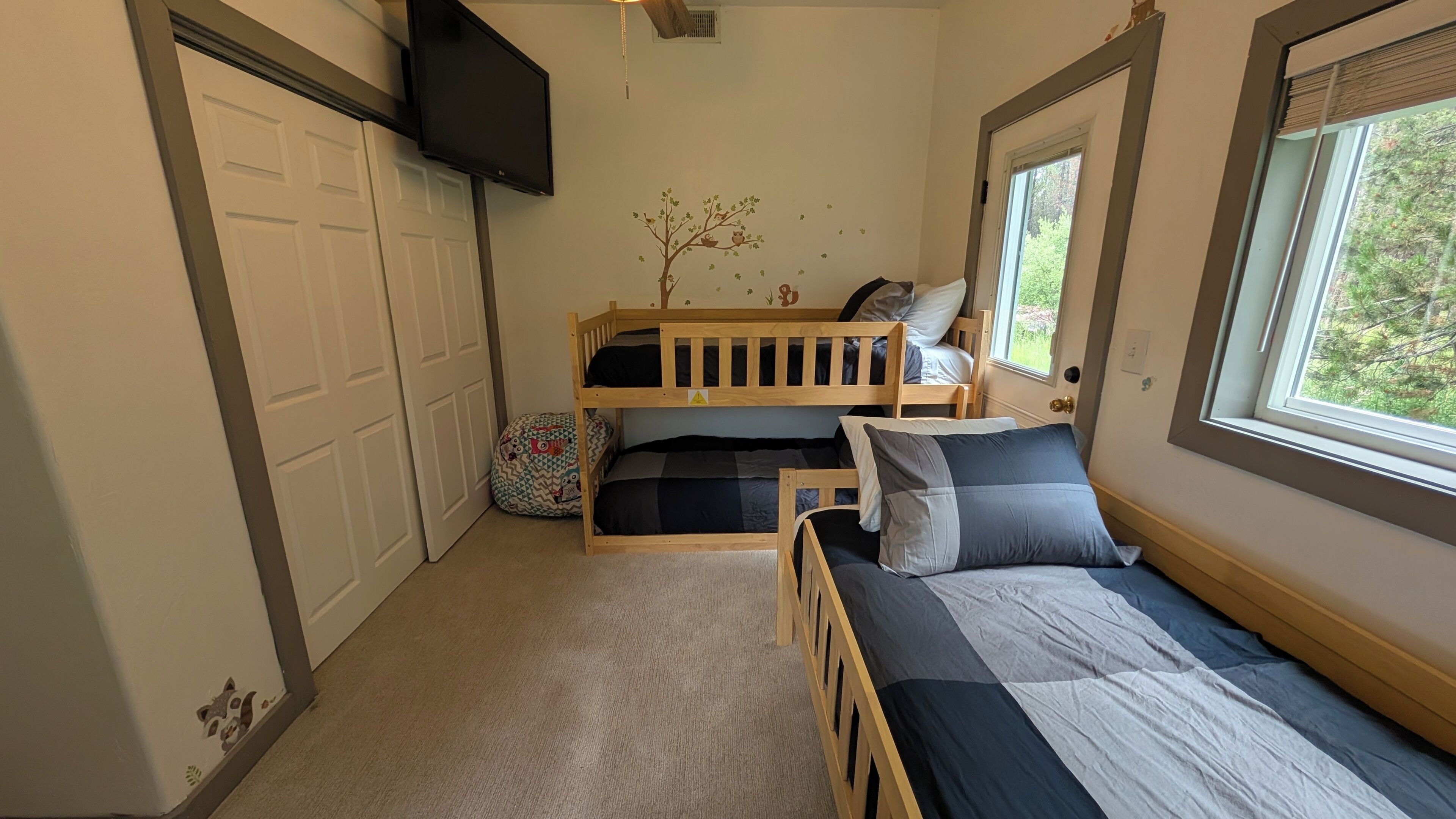 A bedroom with bunk beds, a TV, a window, and a door.