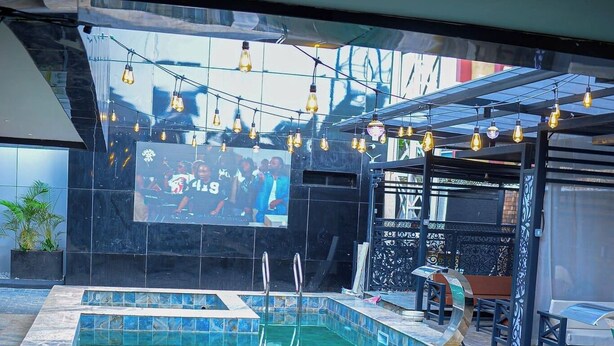 A swimming pool with tiled edges, a metal ladder, and string lights.