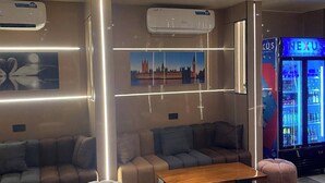 A modern lounge area with seating, tables, and a refrigerator.