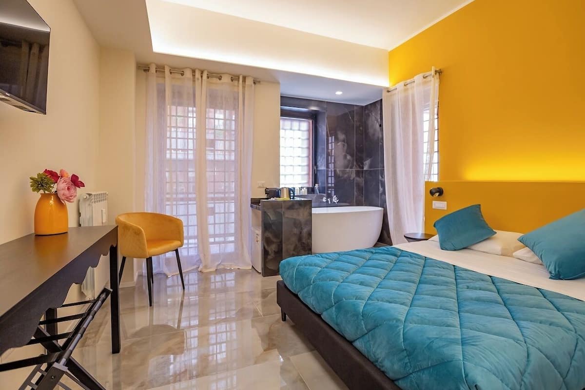 Un dormitorio moderno con cama, escritorio, silla, bañera y ventana con cortinas.