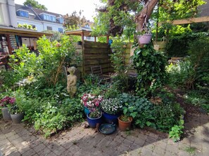 A garden with various plants, a wooden fence, and a statue. - Large, luxurious family home in Haarlem, close to city, beach and Amsterdam. (Haarlem)
