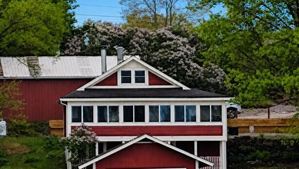 Ein zweistöckiges Haus mit roter Fassade und weißem Dach, gelegen am Wasser.