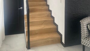 A staircase with wooden steps and black edges, a black door, and a patterned chair. - Equipped house in Liberia for long stays (Liberia)