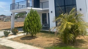 A modern two-story house with a balcony, large windows, and a well-maintained lawn. - Equipped house in Liberia for long stays (Liberia)