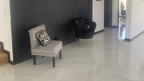 A spacious hallway with a dark accent wall, a patterned armchair, and a black armchair. - Equipped house in Liberia for long stays (Liberia)